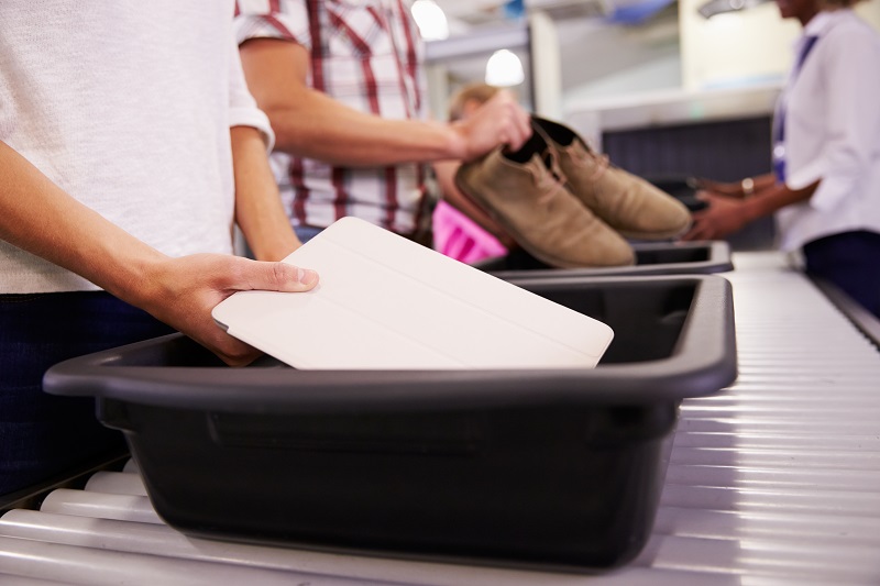 Man puts tablet into tray for airport security check