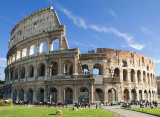 The Colosseum in Rome, Italy is one of the most famous historical buildings and architectural wonders.,a photo of the ancient building stands tall against blue sky with green grass at its base. people can be seen walking around or sitting on horse-drawn carriages to visit it.